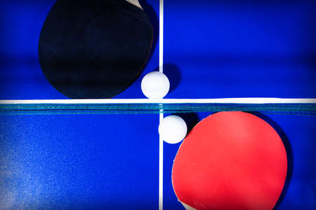 background with rackets and a ball for table tennis on a blue table with white linesの写真素材