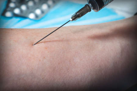 The injection of a drug into the patient's arm with a syringe. Needle for injection close-upの写真素材