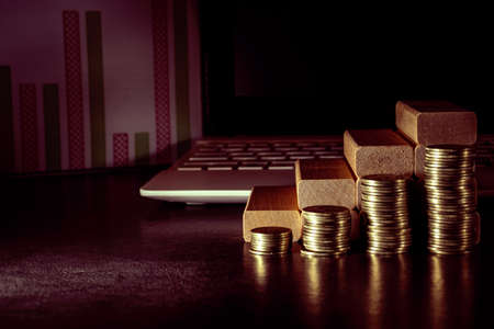 The concept of economic planning. Piles of coins, wooden blocks in the form of steps on the background of a PC keyboard. The idea of a career ladder for successful business development and profit growの写真素材