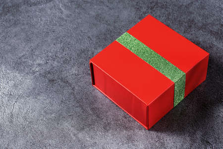 Red gift box with a green ribbon on a gray marble background. View from aboveの写真素材