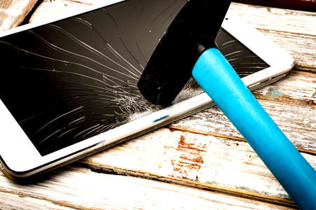 Background with a hammer breaking a tablet screen.の写真素材