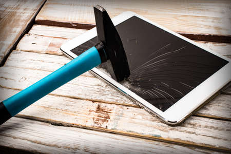 Background with a hammer breaking a tablet screen.の写真素材