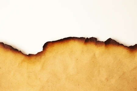 Part of a scroll of old paper with burnt edges closeup on a white backgroundの写真素材