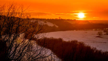 Beautiful sunset with clouds with silhouettes of houses on a hillの写真素材