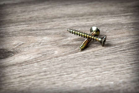 Golden mounting screws close-up on a wooden backgroundの写真素材