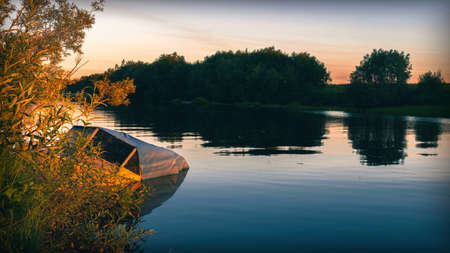 River view with sunken fishing boat at sunriseの写真素材