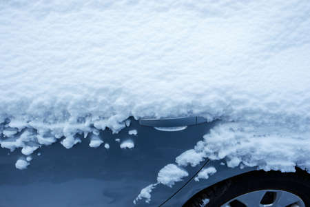 Winter city scene. The car in the parking lot is covered with a layer of white snow. Heavy snowfall.の写真素材