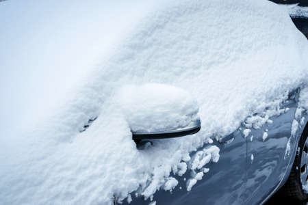 Winter city scene. The car in the parking lot is covered with a layer of white snow. Heavy snowfall.の写真素材