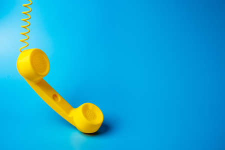 Yellow telephone retro receiver on a blue background. Communication and technologyの写真素材