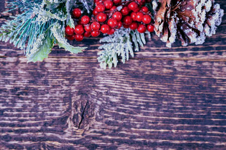 Christmas background with decorations from pine cones, spruce branches and red berries on a wood...