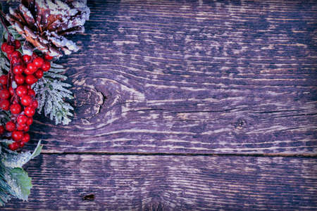 Christmas background with decorations from pine cones, spruce branches and red berries on a wood texture. Copy spaceの写真素材