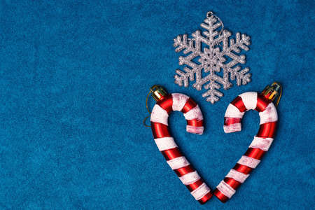 Christmas caramel in the shape of a heart and a snowflake on a blue background. Festive postcard. Copy spaceの写真素材