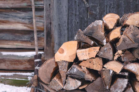 Firewood for the stove lies in a vintage wooden sleigh against the background of a house wall made of old logs. Country lifeの写真素材