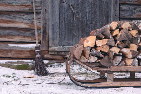 Firewood for the stove lies in a vintage wooden sleigh against the background of a house wall made of old logs. Country lifeの写真素材