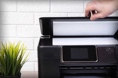 Young mans hand closes the scanner lid with a sheet of white paper on the surface.の写真素材