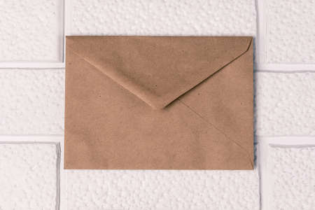 An envelope from old paper on a background of decorative white brickwork. Invitation mockup, vintageの写真素材