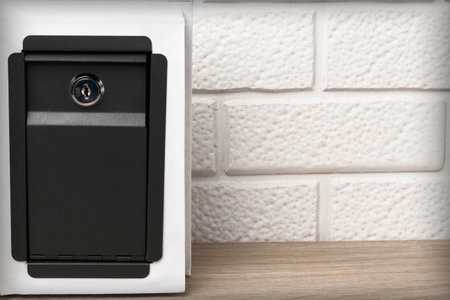 A portable metal safe close-up against a background of white brickwork. Investment security concept