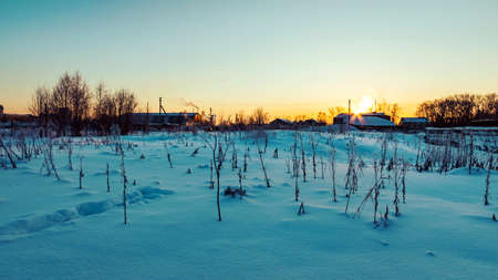 Winter landscape with the setting sun over the snow-capped rooftops. Evening timeの写真素材