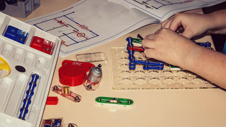 Background with the hands of a child assembling a constructor on the table.