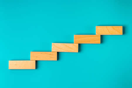 Wooden blocks in the form of steps of a ladder against a background of color of sea water. Business growth conceptの写真素材