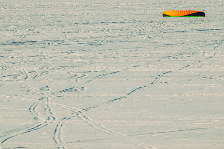 A bright kitesurfing sail lies on the snowy surface of a frozen river. Winter sportsの写真素材