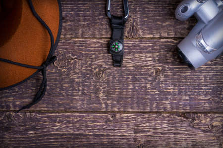 A wide-brimmed hat, a camera and a compass on the background of an old brown wooden surface. Travel and adventure conceptの写真素材