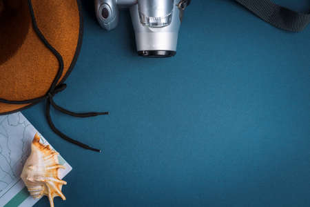 Cowboy hat, camera, geographic map and seashell on a blue background. Travel conceptの写真素材