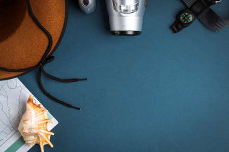 Cowboy hat, camera, geographic map, compass and seashell on a blue background. Travel conceptの写真素材