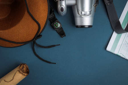 Cowboy hat, camera, compass, geographic map, old paper scroll and seashell on a blue background. Travel conceptの写真素材
