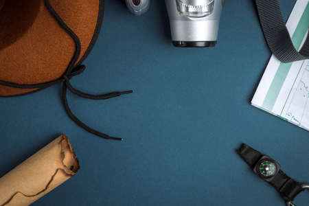 Cowboy hat, camera, compass, geographic map, old paper scroll and seashell on a blue background. Travel conceptの写真素材