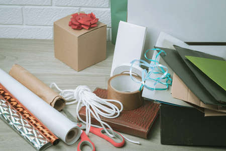 The packing materials lie on a wooden table against the background of a white brick wall. Gift and parcel wrapping.の写真素材