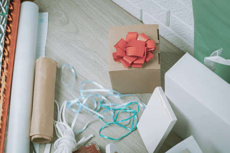 The packing materials lie on a wooden table against the background of a white brick wall. Gift and...