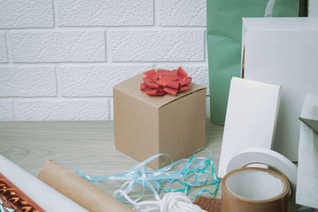 The packing materials lie on a wooden table against the background of a white brick wall. Gift and...