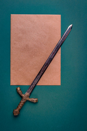 Antique knightly sword and a sheet of old paper on a green velvet background. Vertical positionの写真素材