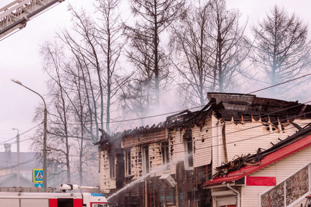 A firefighter extinguishes a fire in a wooden house with water from hoses. Fire fightingの写真素材