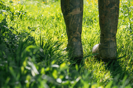 Legs in camouflage boots in the green grass lit by the bright sun.の写真素材
