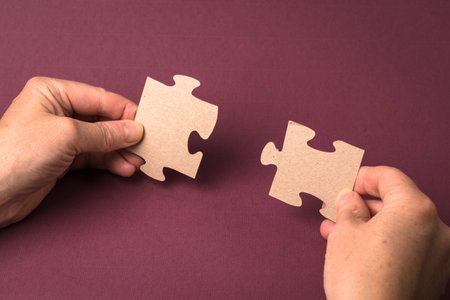 Close-up of a man's hand connecting a puzzle on a purple background. Business solutions, success and strategy conceptの写真素材