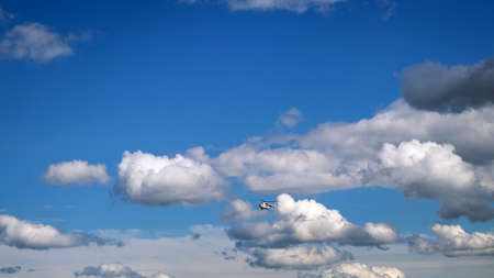 View of the blue sky with white clouds and a flying helicopter.の写真素材