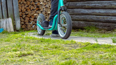 Child's feet on a scooter with large wheels on the background of a village house. Active lifestyleの写真素材