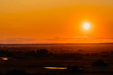 Background with bright orange light from the setting sun over the horizon. Sunsetの写真素材