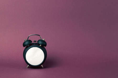 Black alarm clock in retro style on a purple background. Blank white dial.の写真素材