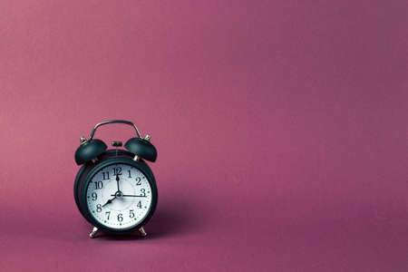 Black alarm clock in retro style on a purple background. Copy space.の写真素材
