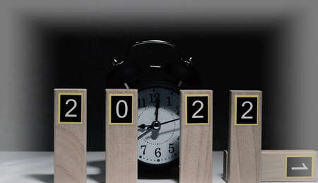 Numbers 2022 on wooden planks and black retro alarm clock on dark background with creative...