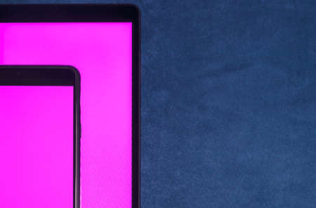 A smartphone with a blank purple screen lies on the tablet screen on a blue velvet background. Copy spaceの写真素材