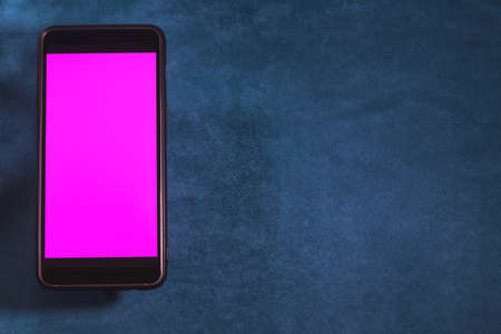 Smartphone with blank purple screen on blue velvet background. Copy spaceの写真素材