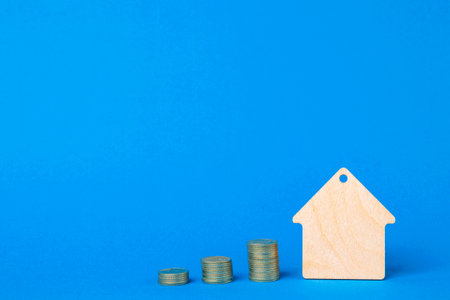 Keychain Wooden house and stacks of coins on a blue background.の写真素材