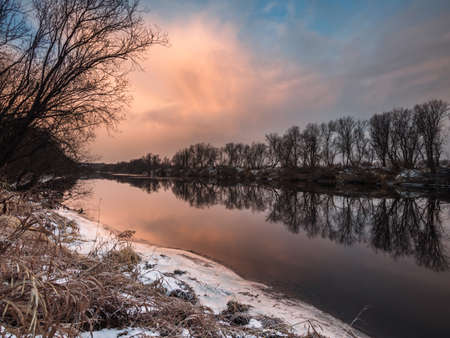 Morning in pink tones on the river starting to freeze. Trees on the shoreの写真素材