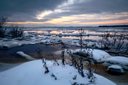 Beautiful sunrise over the river with floating ice floes. Calm morning landscapeの写真素材