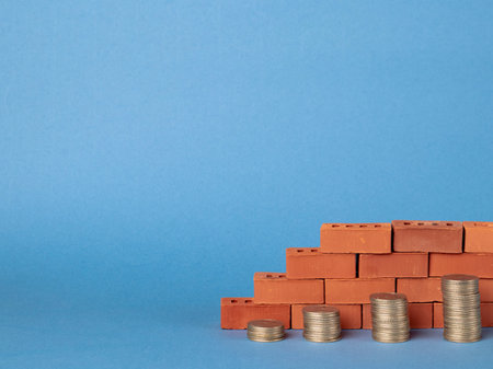 Stacks of coins in the form of steps against a background of blocks of red bricks.の写真素材