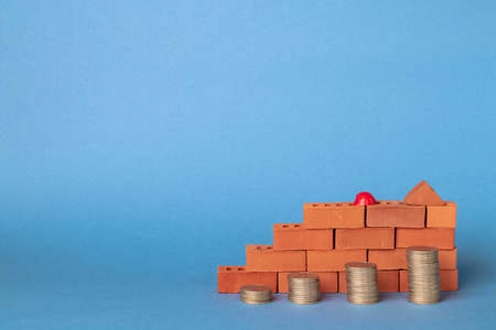 Stacks of coins in the form of steps against a background of blocks of red bricks.の写真素材